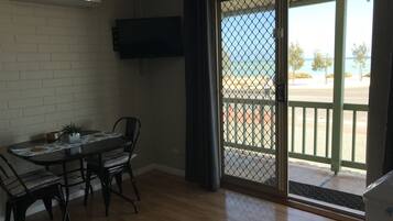A room with a dining table, chairs, a TV mounted on the wall, and a sliding glass door leading to an outdoor area.