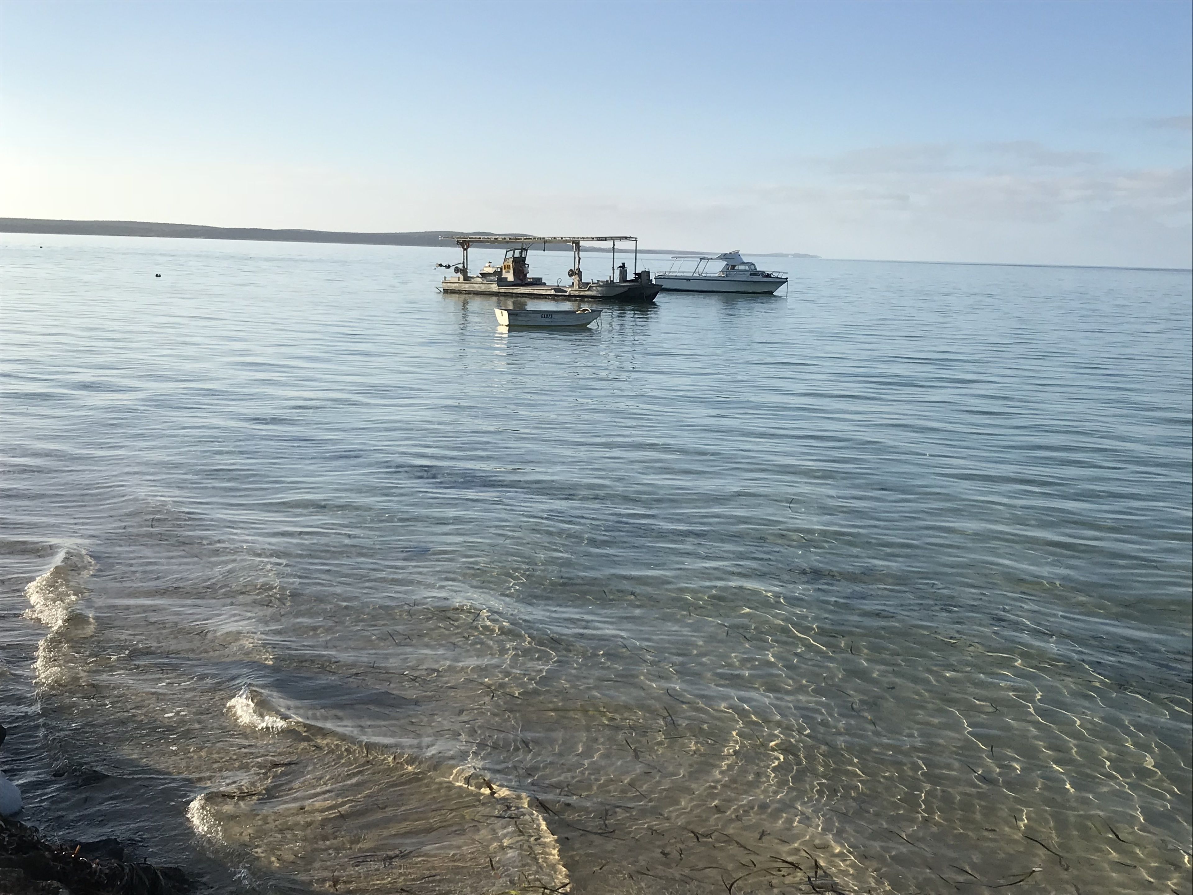 Un lago tranquilo con dos barcos anclados.