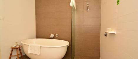 A modern bathroom with a freestanding bathtub, a glass shower enclosure, and a small wooden stool.