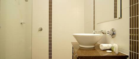 Un baño moderno con un lavabo blanco grande, un espejo y una zona de ducha.