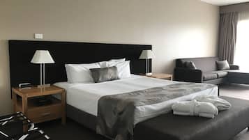 Una habitación de hotel con una cama grande, dos mesitas de noche, una silla y un sofá.