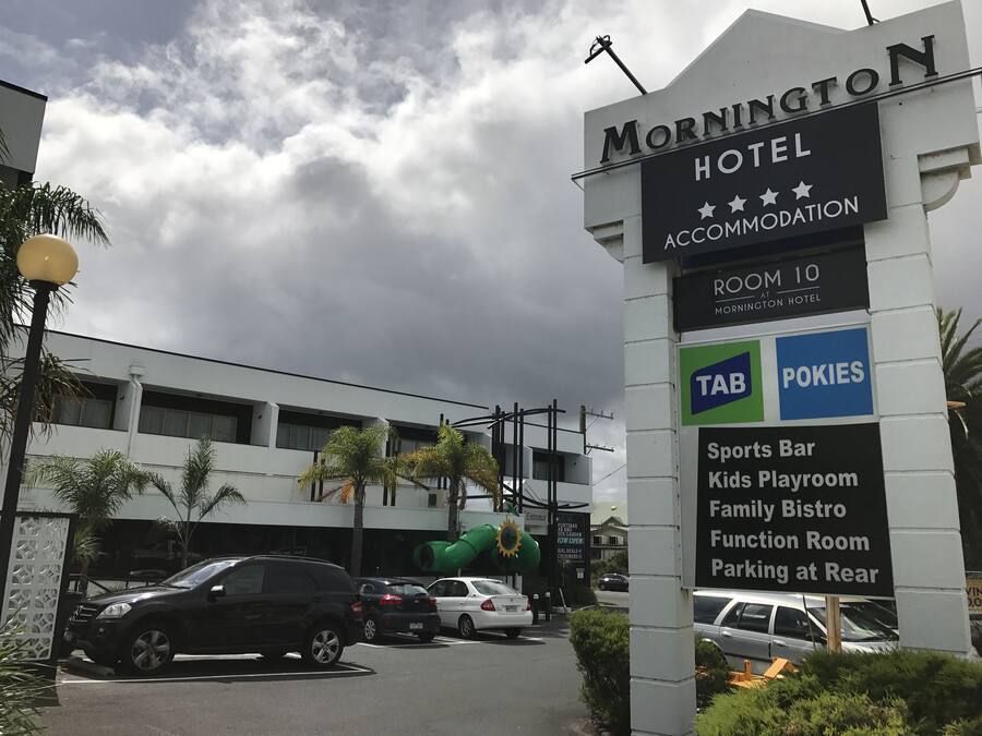 A hotel sign with amenities including a sports bar, kids playroom, family bistro, function room, and parking at the rear.