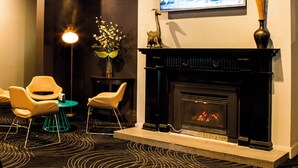 Un área de estar moderna con chimenea, asientos cómodos y un televisor montado en la pared.