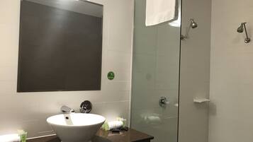 Un baño con un espejo grande, un lavabo blanco y una cabina de ducha de vidrio.