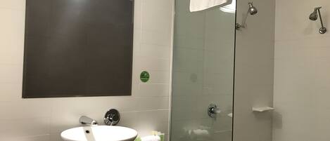 A bathroom with a large mirror, a white sink, and a glass shower enclosure.
