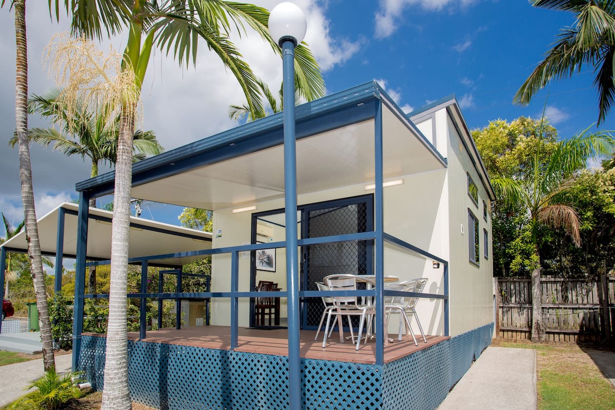 A modern house with a covered patio, a dining area, and a fenced backyard.