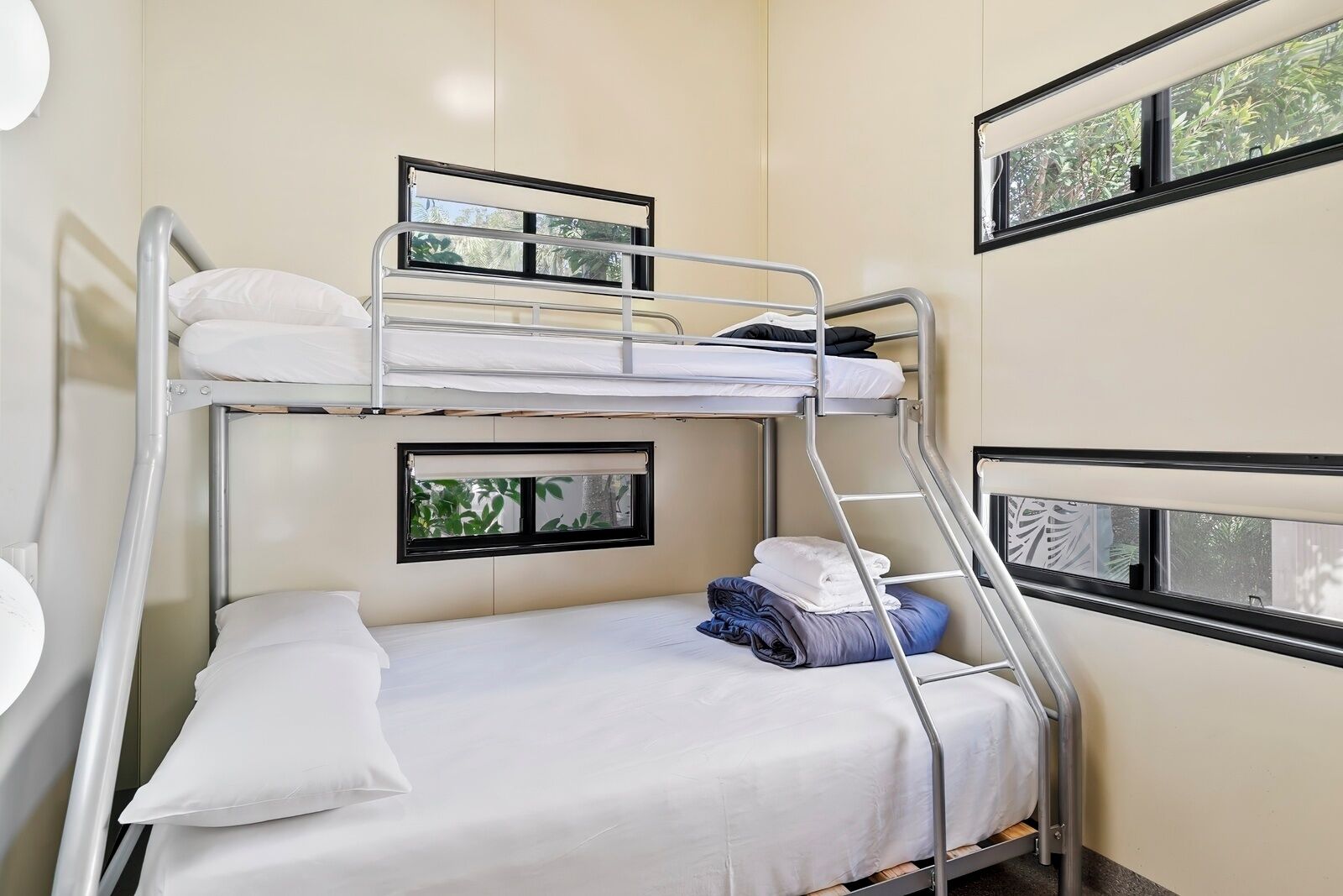 A bunk bed room with a window, a small table, and a chair.