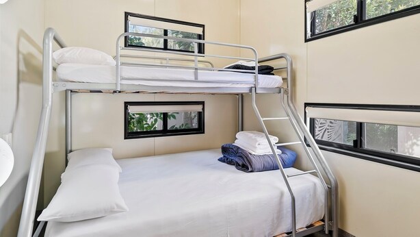 A bunk bed room with a window, a small table, and a chair.