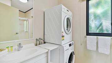 Bagno d'albergo con doppio lavabo, lavatrice, specchio e finestra vista.