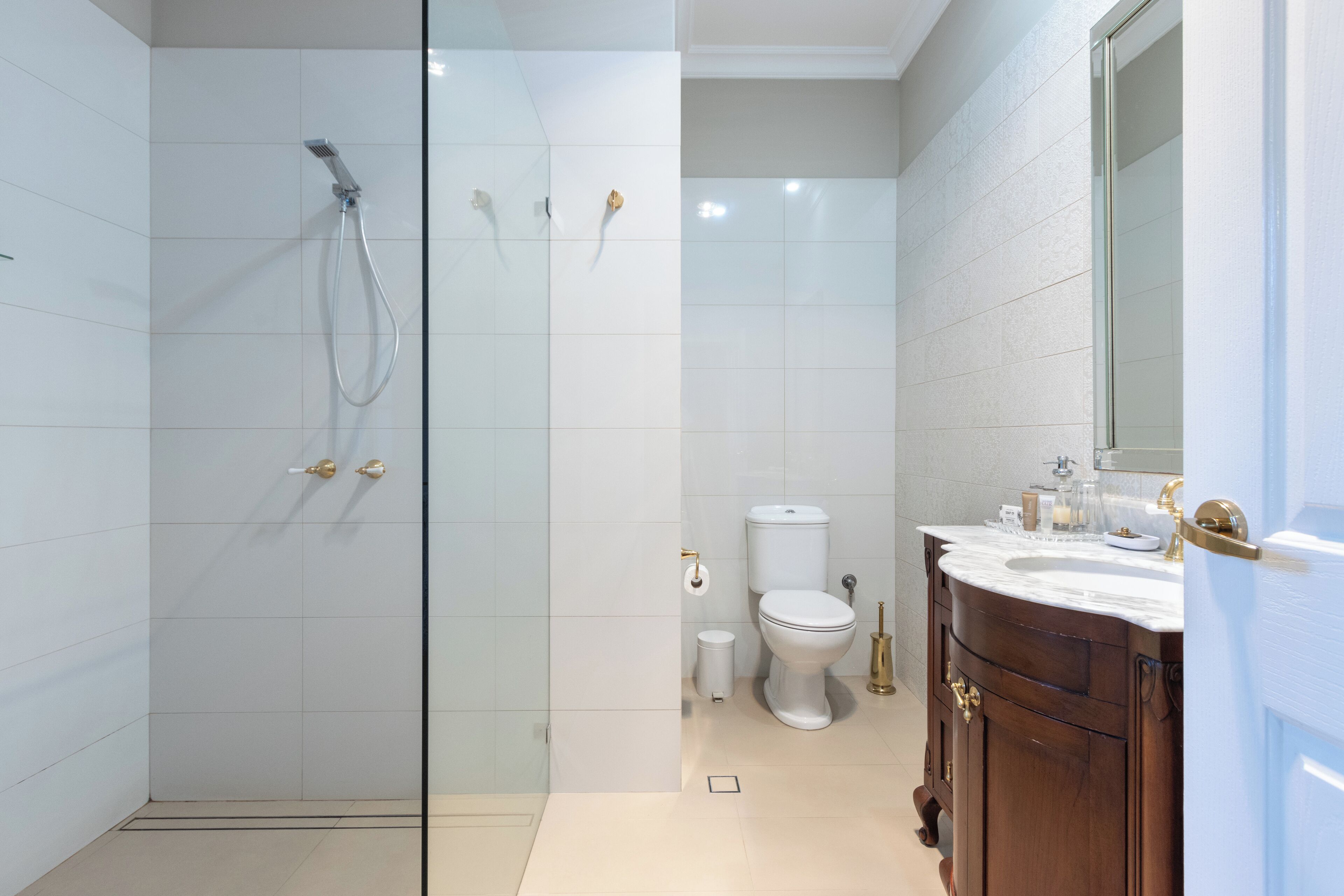 Une salle de bain moderne avec une douche à parois de verre, des toilettes blanches et un meuble-lavabo en bois avec un miroir.