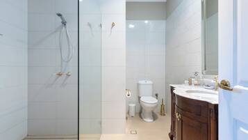 Une salle de bain moderne avec une douche à parois de verre, des toilettes blanches et un meuble-lavabo en bois avec un miroir.