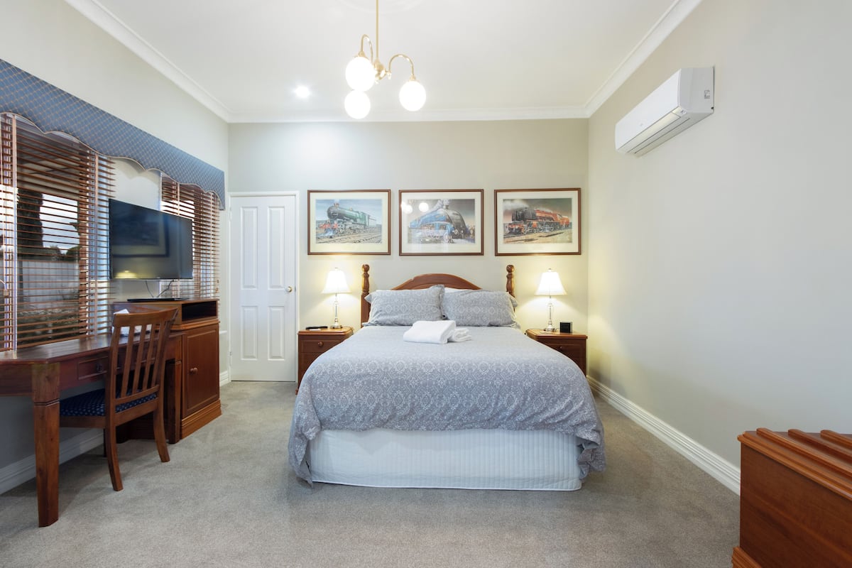 A bedroom with a bed, bedside tables, a desk, and a chair.