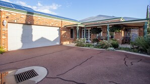 A residential property with a garage, brick exterior, green roof, and a landscaped garden.