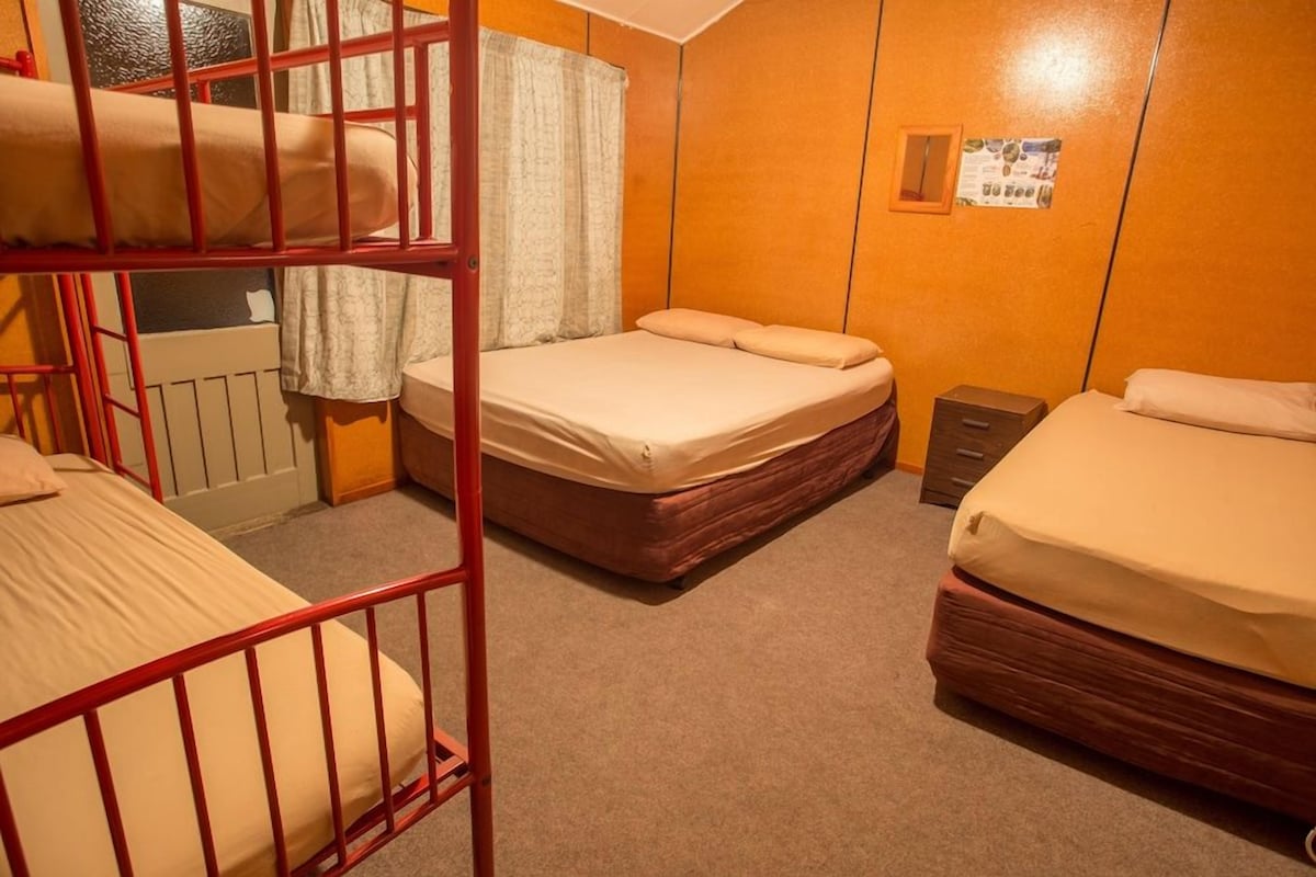 Une chambre de dortoir avec des lits superposés, un lit simple et une petite armoire.
