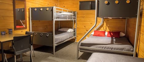 A room with bunk beds, a desk, and a chair.