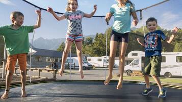 A trampoline with four children jumping.