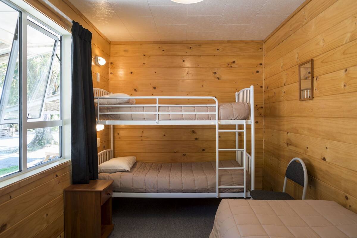 Habitació amb literes, una finestra, taula petita i una cadira.