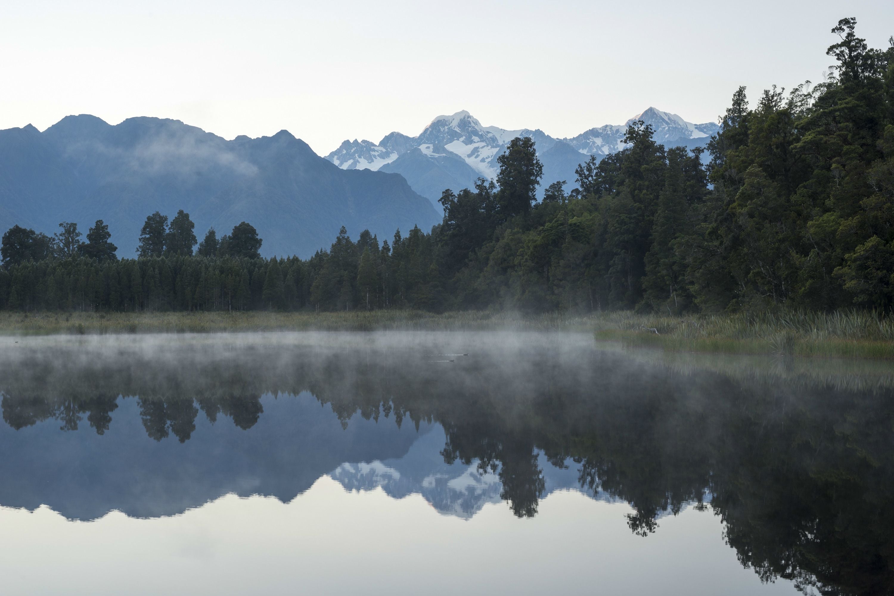A calm lake reflecting mountains and trees.