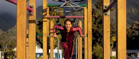 A person using a playground structure with a metal frame and wooden beams.