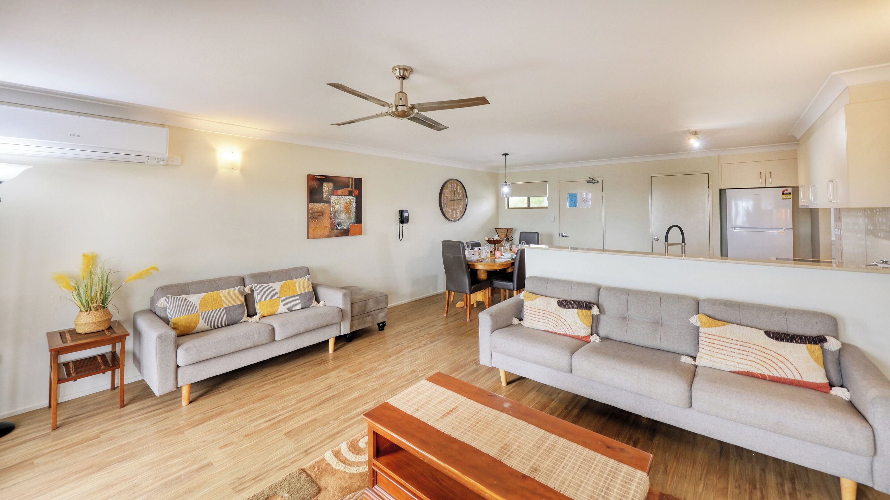 A spacious living area with two sofas, a dining table, and a kitchen area.