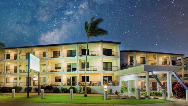 Un hotel de varios pisos con balcones, entrada cubierta y un cielo estrellado.