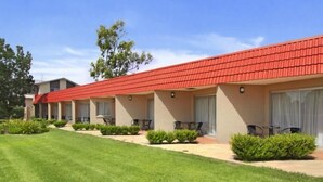 A motel with a red roof, multiple rooms with windows, and a well-maintained lawn. - Country Capital Motel (South Tamworth)