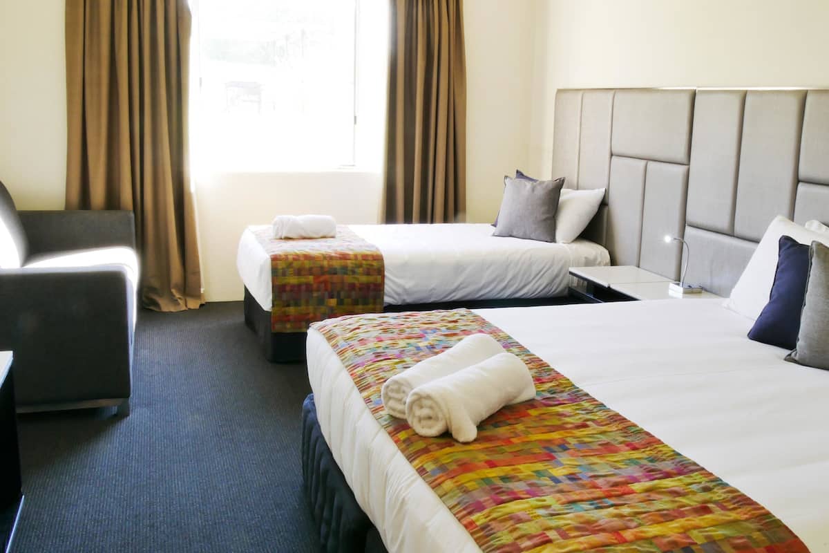 A hotel room with two beds, a desk, and a chair.