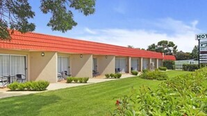 A motel with a red roof, multiple rooms, and a well-maintained lawn. - Country Capital Motel (South Tamworth)