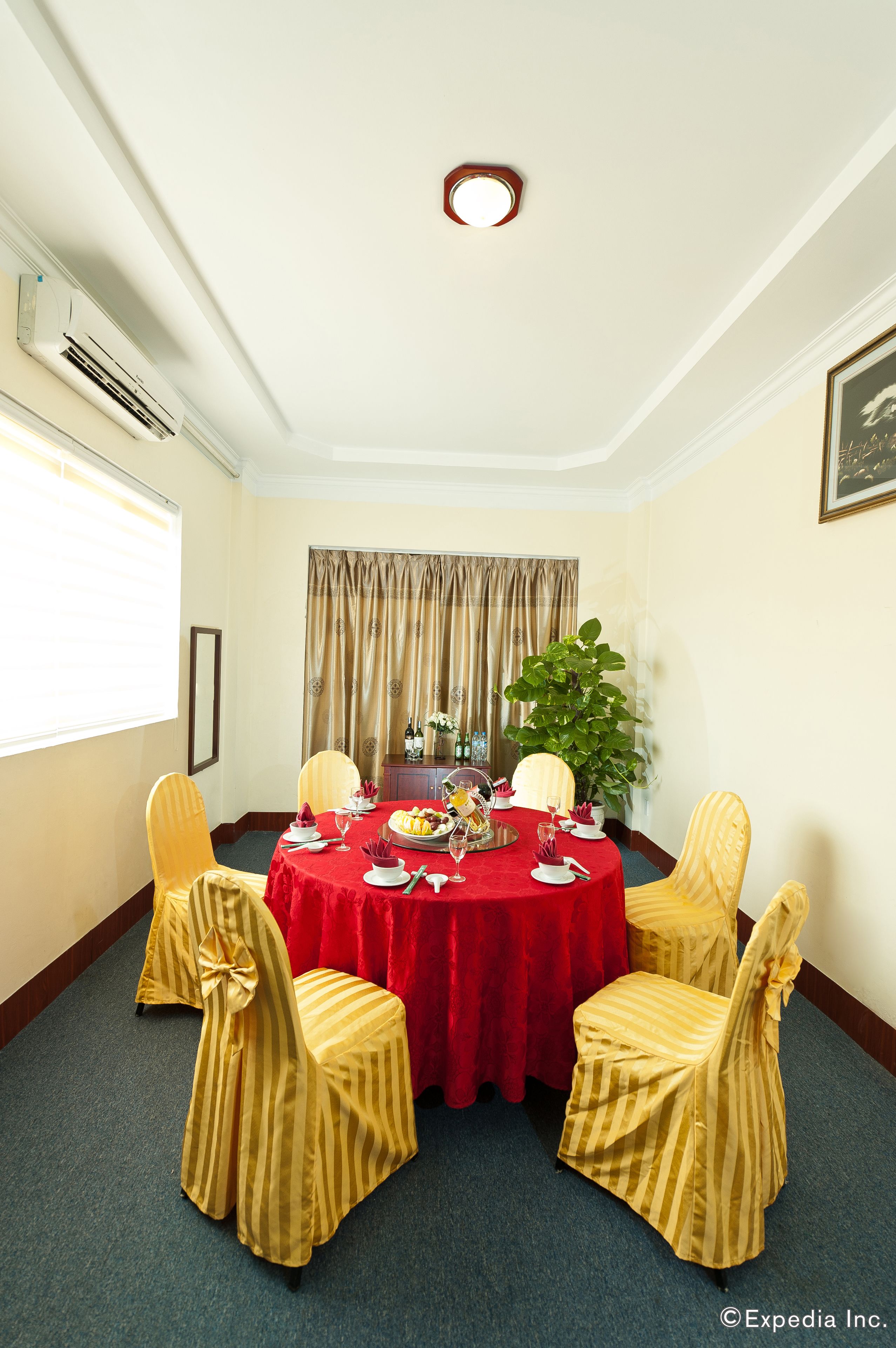 A conference room with a round table, four chairs, a red tablecloth, and a potted plant.