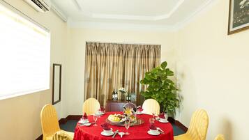 A conference room with a round table, four chairs, a red tablecloth, and a potted plant.
