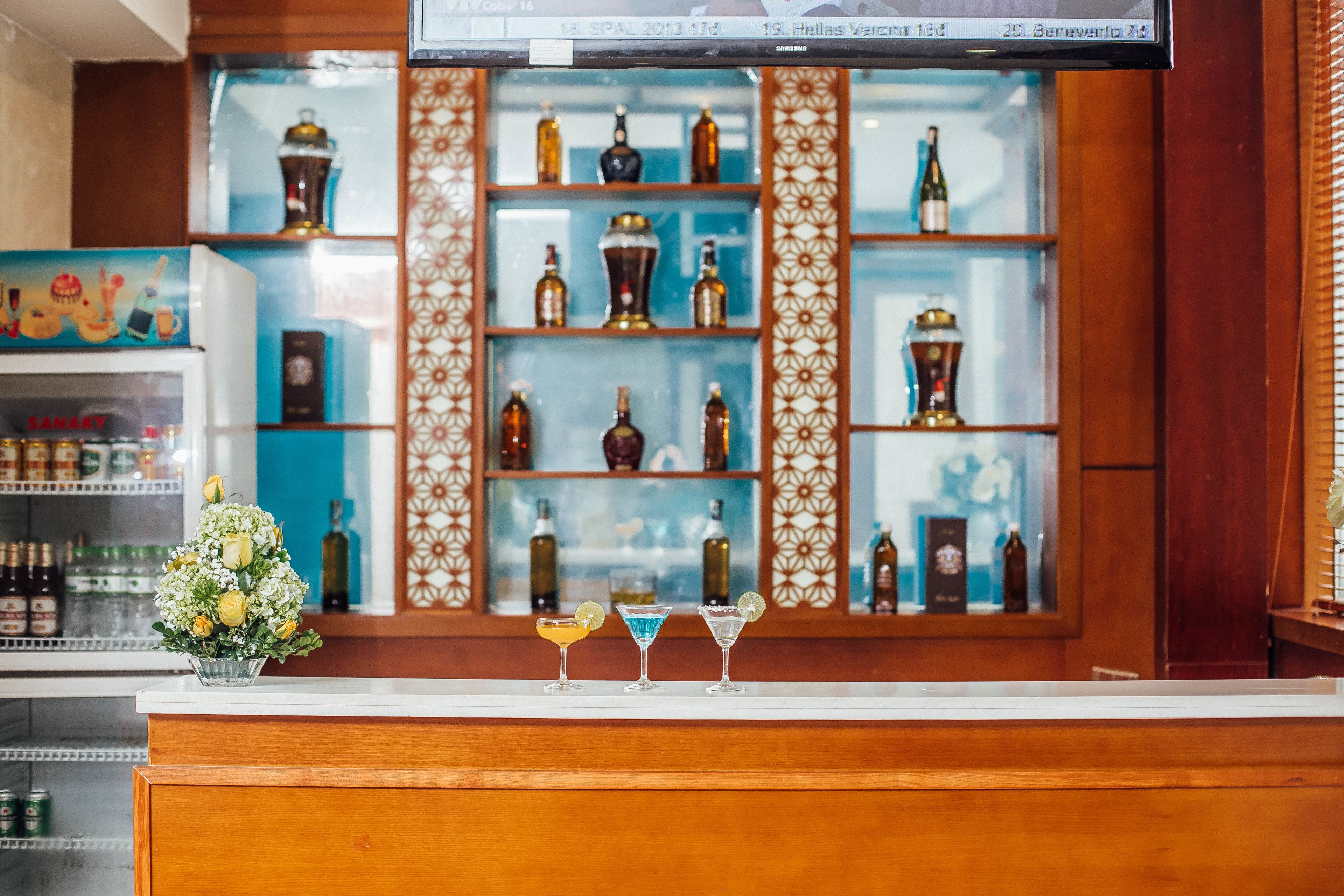 A bar area with a wooden counter, shelves with bottles, and a decorative glass display.