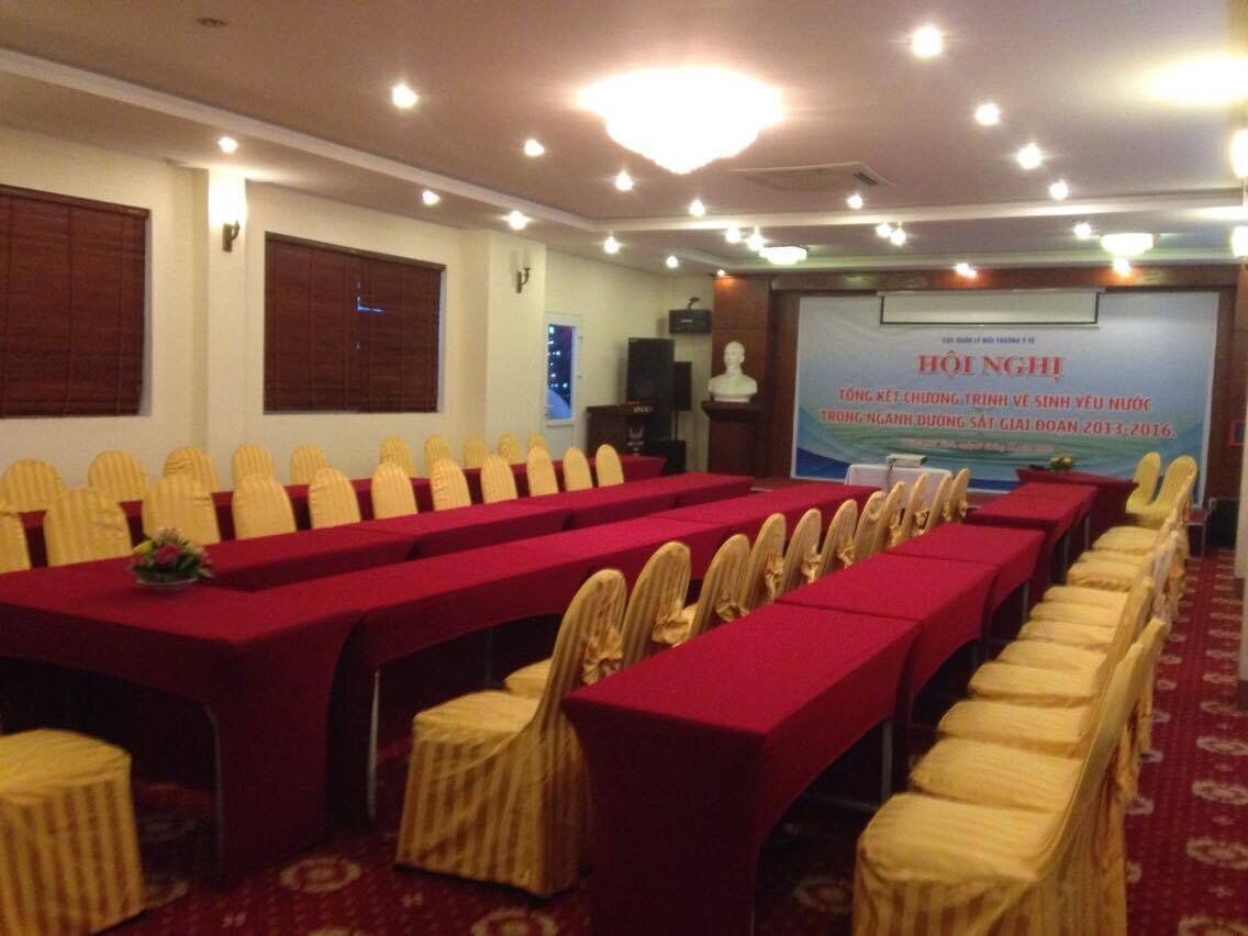 A conference room with rows of tables and chairs, a projector screen, and a podium.