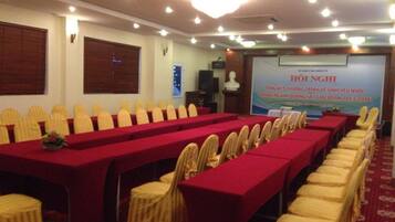 A conference room with rows of tables and chairs, a projector screen, and a podium.