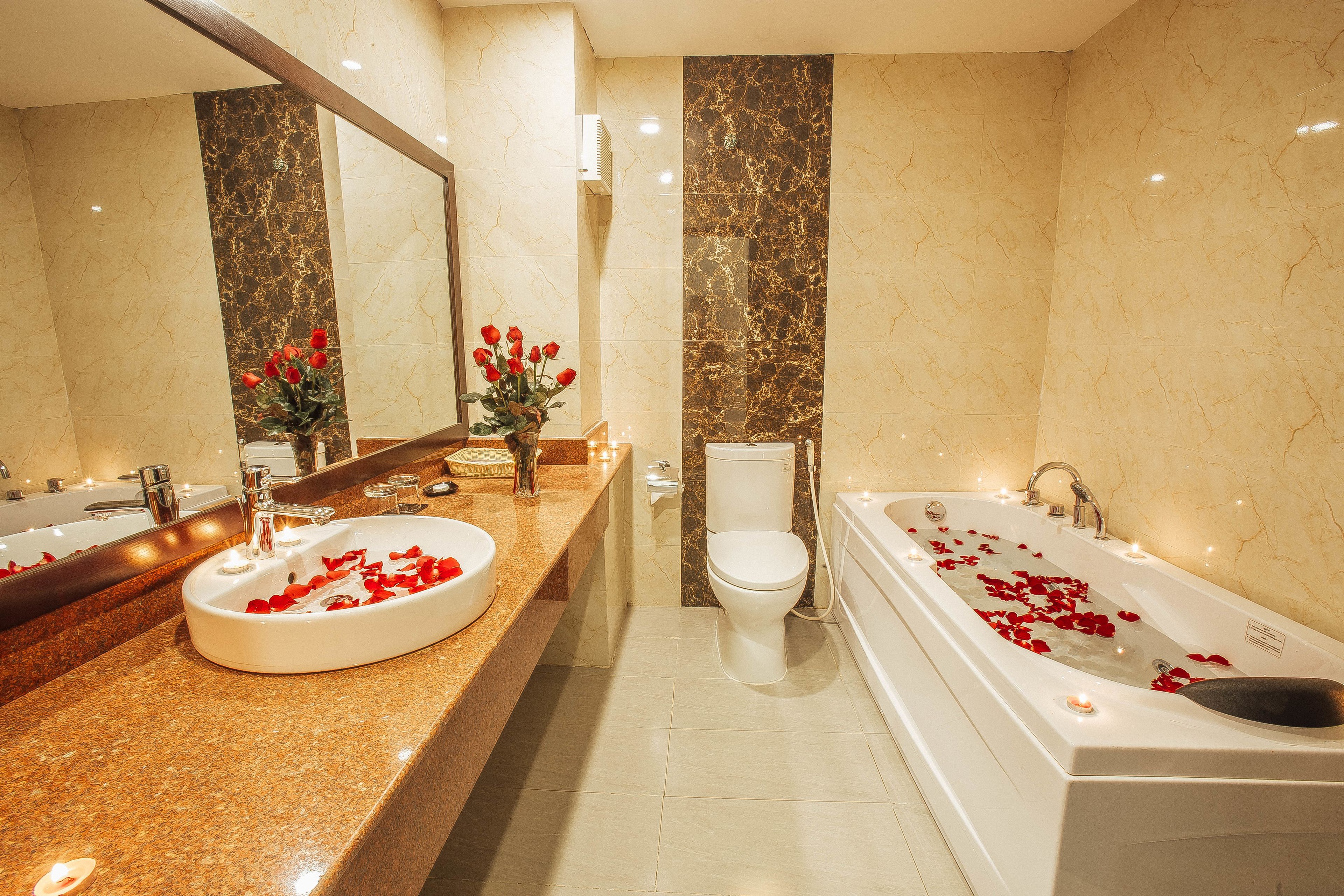 Un bagno con un vanità in marmo, un WC e una vasca da bagno con petali di rosa.