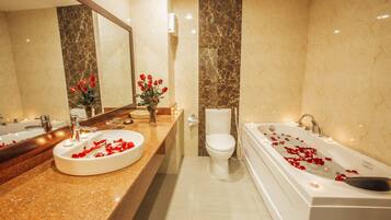 Un bagno con un vanità in marmo, un WC e una vasca da bagno con petali di rosa.