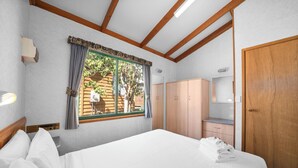 Una habitación de hotel con cama, ventana con cortinas, armario y puerta.