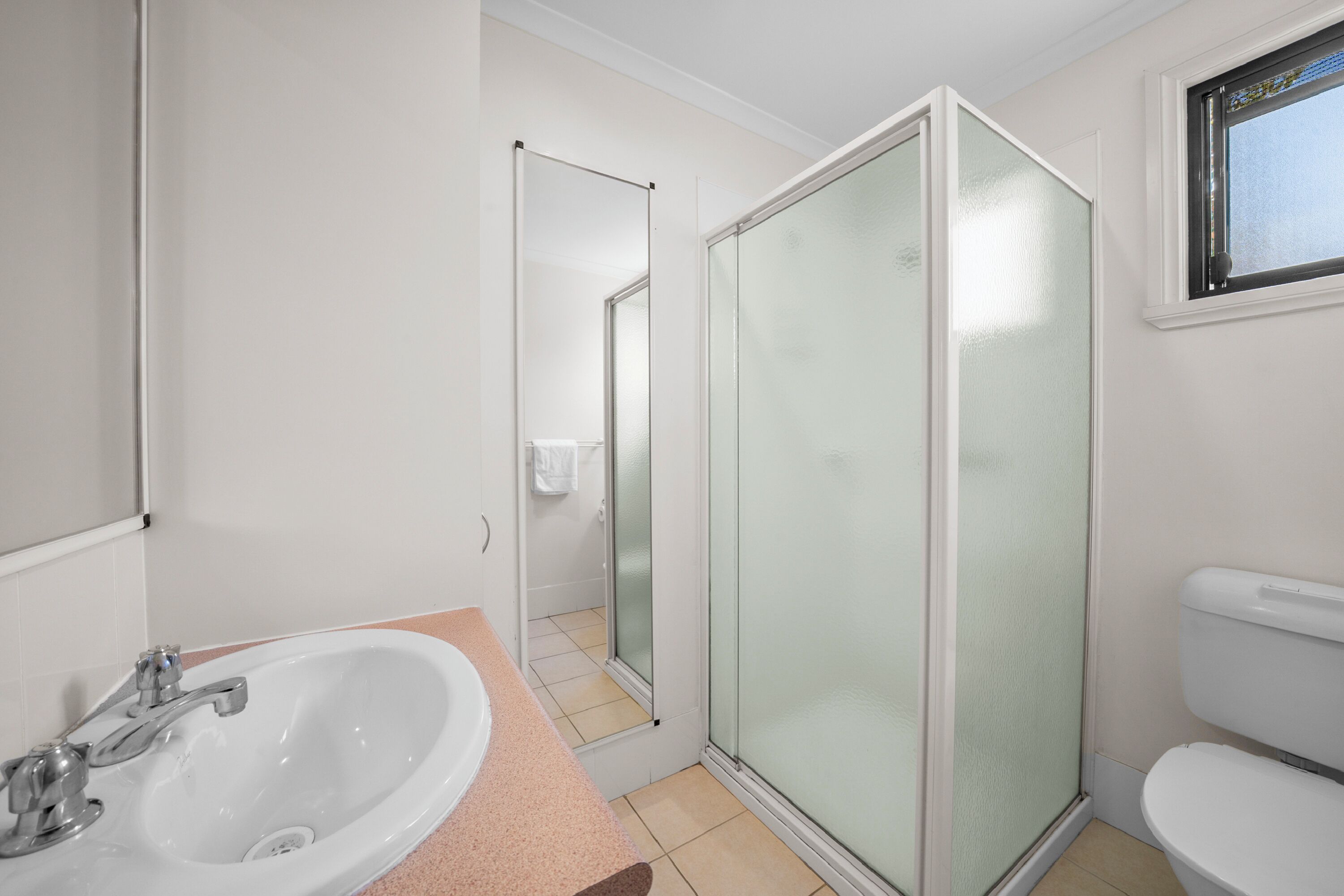 Une salle de bain équipée d’un lavabo, de toilettes et d’une douche à parois de verre.