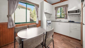Una cocina compacta con mesa, sillas, microondas y estufa.