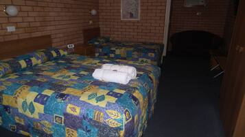 Habitación de hotel con dos camas, una pared de ladrillo, un cuadro pequeño y un escritorio.