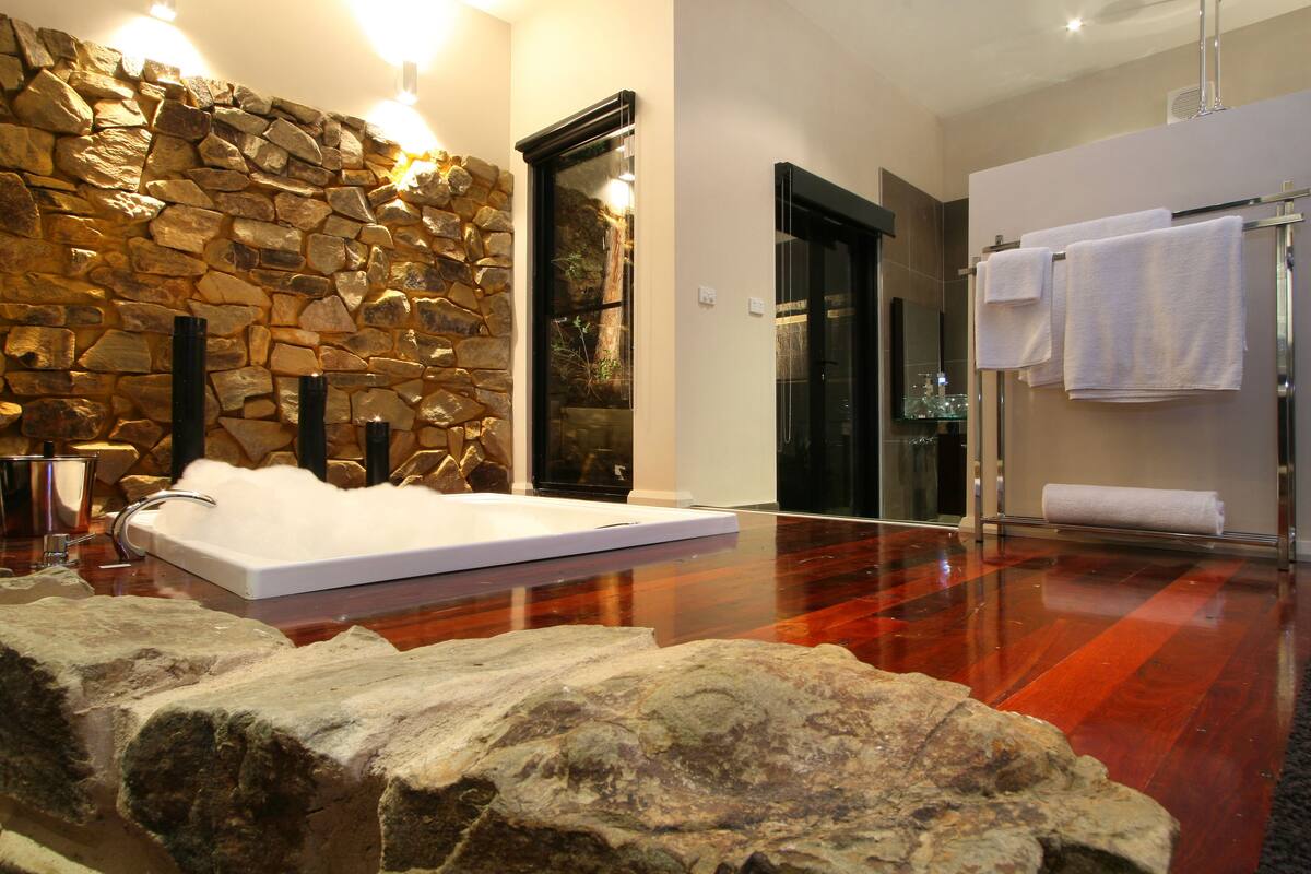 A bathroom with a stone wall, a bathtub, and a towel rack.