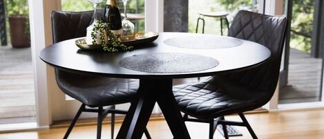 A round table with a black leather chair, a bottle of champagne, and a tray with glasses.