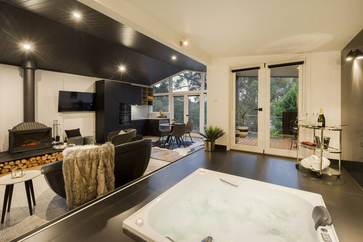 A modern living room with a fireplace, a large window, and a hot tub.