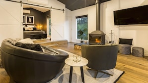 Una sala de estar moderna con chimenea, sofás de cuero y un televisor grande.