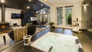 Una sala de estar moderna con una chimenea grande, un rincón de descanso acogedor y un amplio patio exterior.