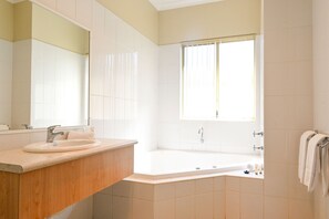 Une salle de bain moderne avec un lavabo, un miroir et une baignoire.
