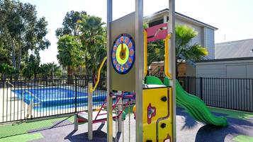 A playground with a slide, climbing structures, and a pool.