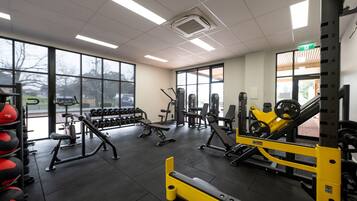 Una palestra con diverse attrezzature per esercizi, ampie finestre e un layout pulito e ordinato.