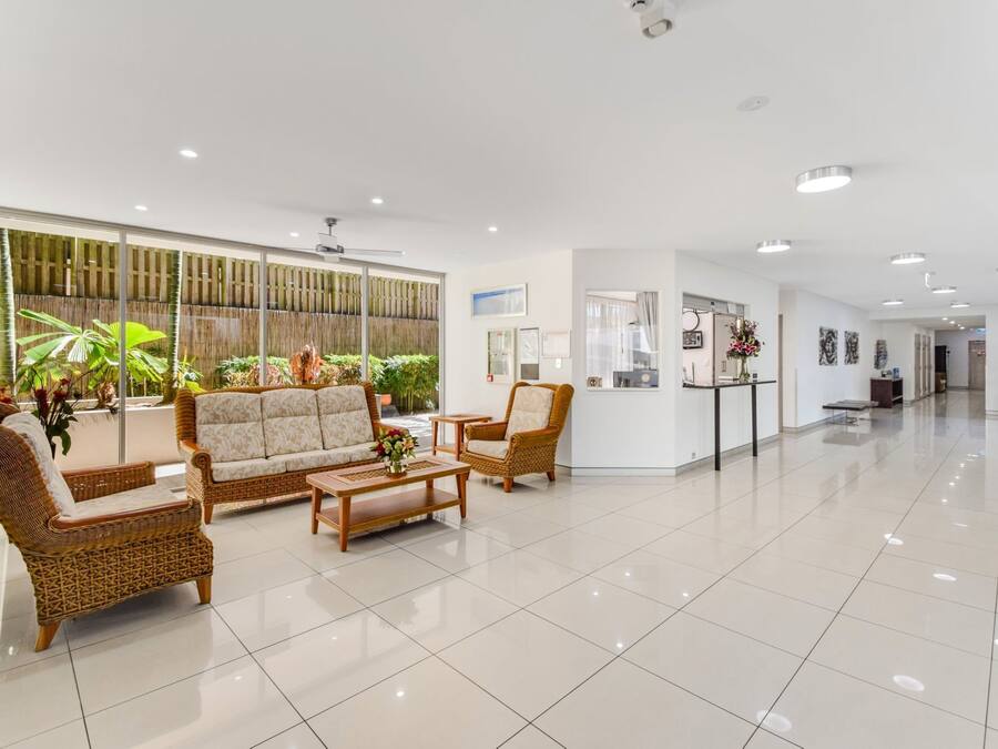Eine großzügige Lobby mit einer Rezeption, Korbmöbeln und einem großen Fenster mit Pflanzen.