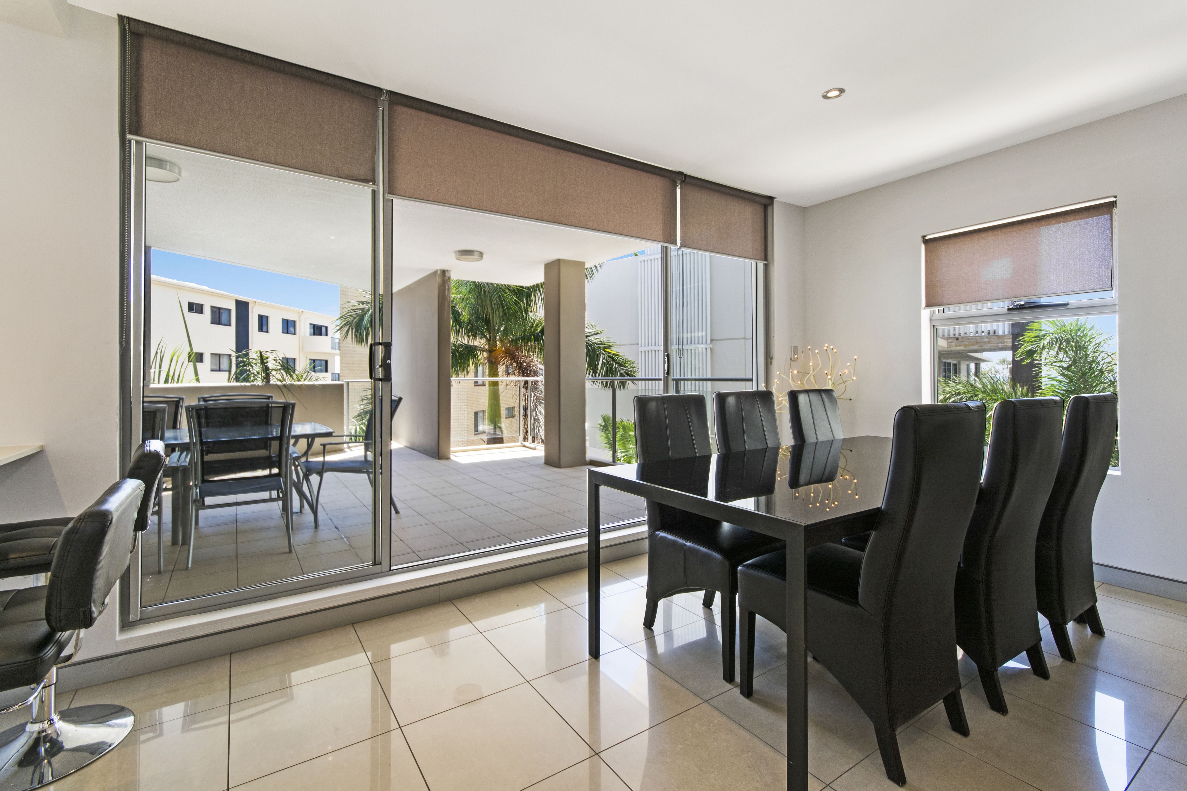 A modern dining area with a glass partition, a table with chairs, and a view of the outside.