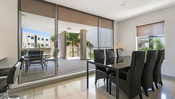Un espace repas moderne avec une cloison en verre, une table avec des chaises et une vue sur l’extérieur.